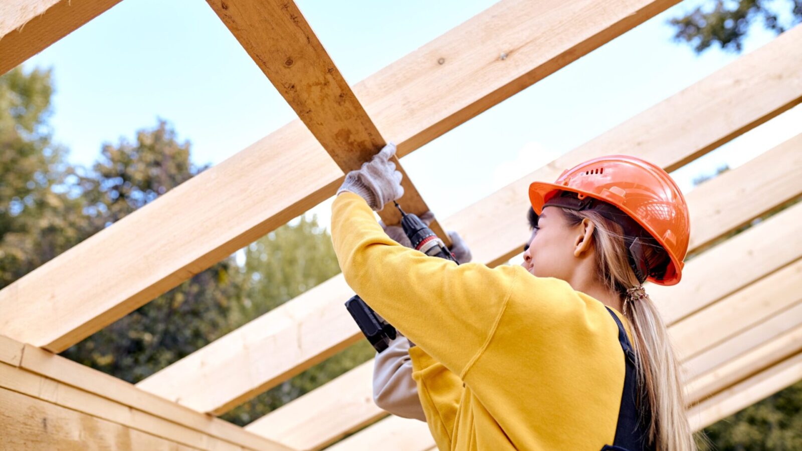 Professionnelle du bâtiment assemblant une structure en bois sur un chantier